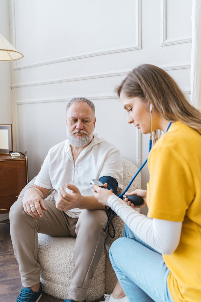 woman-and-man-with-sphygmomanometer-7345474 A healthcare professional checks an elderly mans blood pressure in a cozy room.